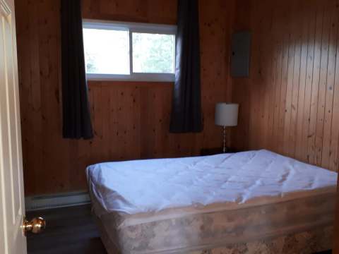 This rustic bedroom is furnished with a comfortable bed and features wood-paneled walls.