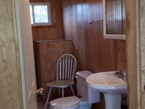 The cottage bathroom features a pedestal sink and a toilet.