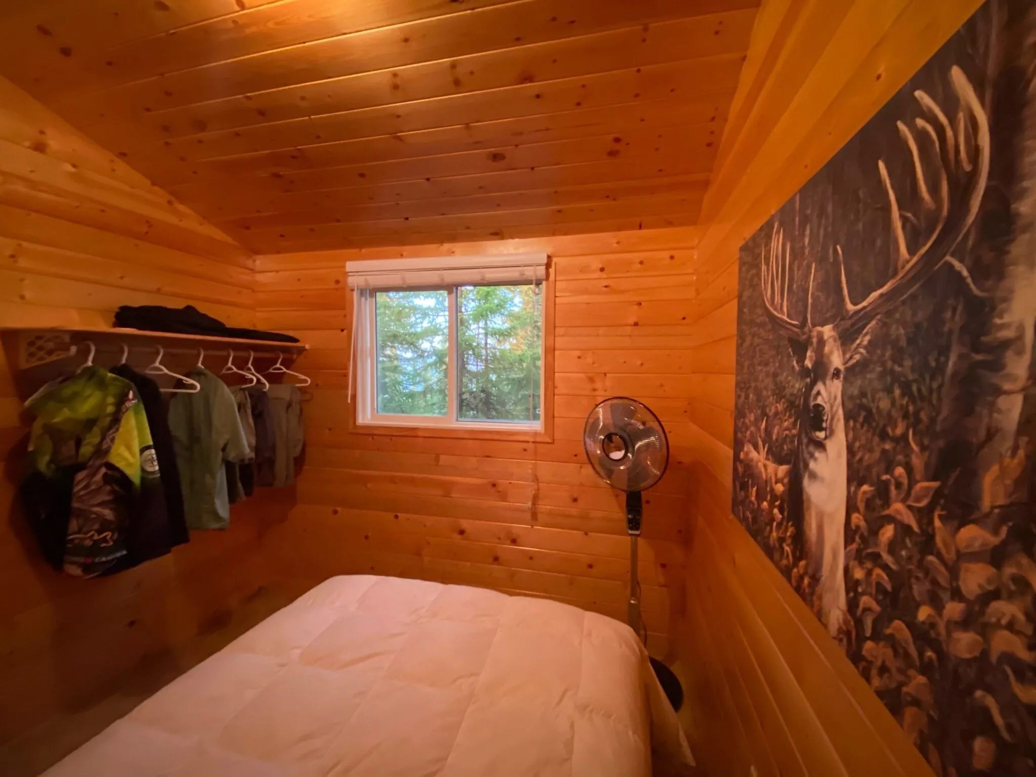 A comfortable bedroom with a bed, open storage, and wooden wall decor.